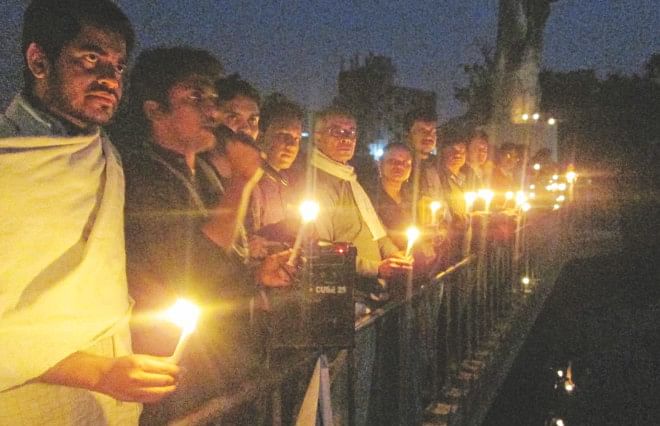 Members of Prothom Alo Bondhusabha's Chandpur unit alongside people from all walks of life form a human chain at the base of Ongikar in Chandpur city yesterday bearing candles and chanting the slogan 