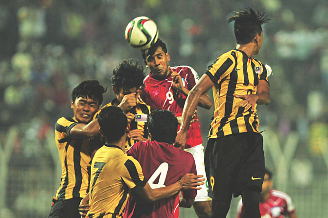 Booters of Bangladesh (in red shirts) and Malaysia are locked in an aerial battle during the opening match of the Bangabandhu Gold Cup football tournament in Sylhet yesterday. Even the support of a full-house at the stadium failed to inspire Bangladesh, as the home side lost the game 1-0. Photo: FIROZ AHMED