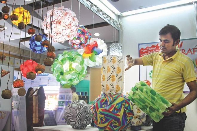 Abul Kalam Azad, owner of Craft All BD, a producer of home decor items, displays lamp shades at an entrepreneurship and innovation expo organised by DCCI and Bangladesh Bank at Bangabandhu International Conference Centre in Dhaka yesterday.  Photo: star