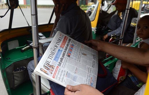 A commuter in an auto-rickshaw holds up a copy of an English-language Indian newspaper, with the headlines on exit polls  Exit poll results are dominating headlines in India. Photo: BBC