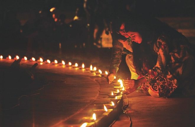 Two mourners light earthen lamps at the capital's Rabindra Sarobar yesterday evening in memory of the 74 people, including 57 army officers, who were massacred during the BDR mutiny at Pilkhana on February 25-26, 2009. Family members as well as general people paid their tributes to the slain people, marking the fifth anniversary of one of the country's worst bloodbaths. Photo: Star