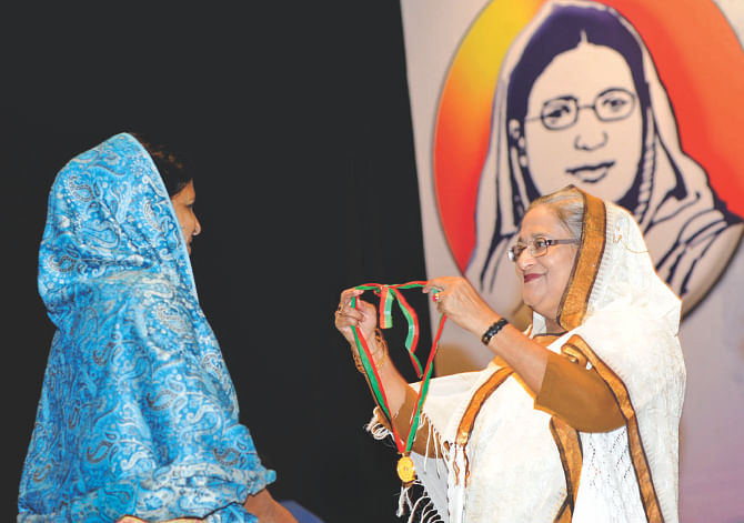 Prime Minister Sheikh Hasina presents Begum Rokeya Padak to Golap Banu, founder of Baridhara Mohila Samabaya Samity in Dhaka, for her contributions to spreading female education, establishing women's rights and socio-economic development of the helpless and poor women, in Osmani Memorial Auditorium of the capital yesterday. Photo: BSS