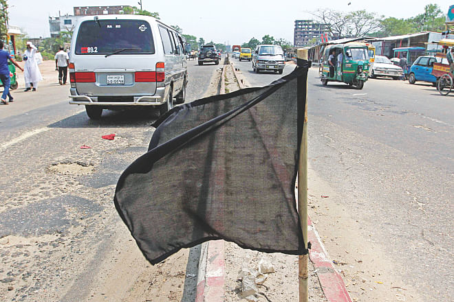 A black flag flutters on the central reservation at Signboard area of Narayanganj yesterday. The flag was one of hundreds the people of the district hoisted on streets and intersections to mourn the seven people recently abducted and murdered, including councillor Nazrul Islam. Photo: Anisur Rahman