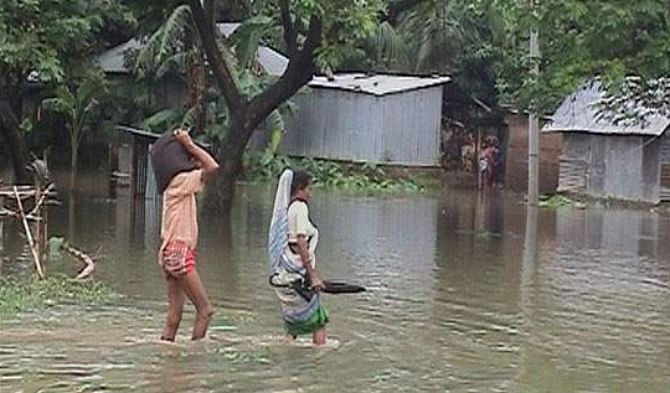 A woman and a man wade through floodwater at Birishiri village in Durgapur upazila of Netrakona. PHOTO: STAR