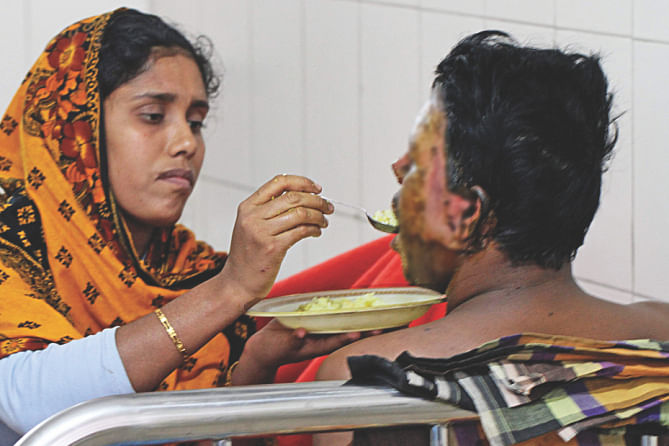 Unable to use his burnt hands, one victim being fed by his wife. Photo: Star