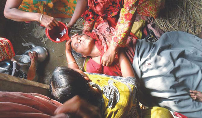 Relatives and neighbours help Shefali Khatun, the mother of truck helper Hasib Hossain, regain her consciousness yesterday, at Sonamukhi village in Sirajganj. She collapsed seeing the body of her son, a 30-year-old burnt to death in a petrol bomb attack in Bogra the day before. The victim's father said Hasib was the main earning person of the five-member household. He got married to Yeasmin Bizli two years ago and the couple had a son three months back.  Photo: Star
