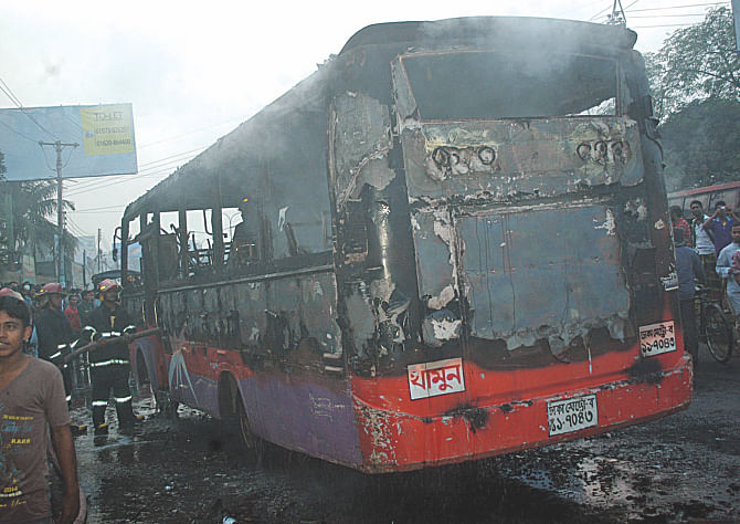 A bus which alleged pickets torched at Gabtoli Bus Terminal in the capital yesterday. Firemen are seen pumping water into the bus to stop the smoldering. Photo:  Banglar Chokh 
