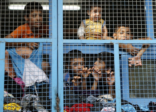 Displaced Palestinian children from Beit Hanun in the northern Gaza Strip stand behind the window of a classroom yesterday at a UN school in the refugee camp of Jabalia where families have taken refuge after fleeing heavy fighting in the Gaza Strip.  Photo: AFP