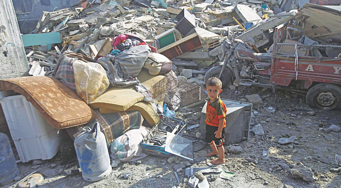 A Palestinian boy stands next to the wreckage of a building, which was hit in an Israeli strike, in the southern Gaza Strip yesterday. A fresh wave of violence killed dozens in Gaza after the collapse of a UN and US backed ceasefire. Photo: AFP
