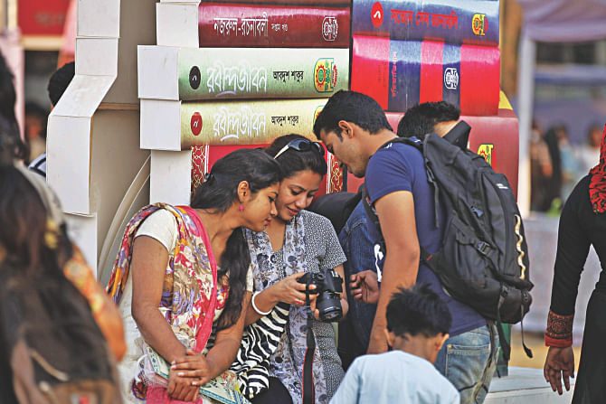 Visitors engrossed in photos they took at the Suhrawardy Udyan portion of Amar Ekushey Granthamela-2015 yesterday. Apart from books, the fair is a source of amusements for many. Photo:  Star