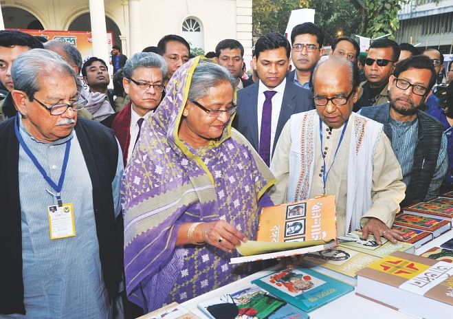 Prime Minister Sheikh Hasina flips the pages of a book at a stall in Ekushey Boi Mela in the capital yesterday right after the inaugurating the month-long book fair at Bangla Academy compound.  Photo: BSS