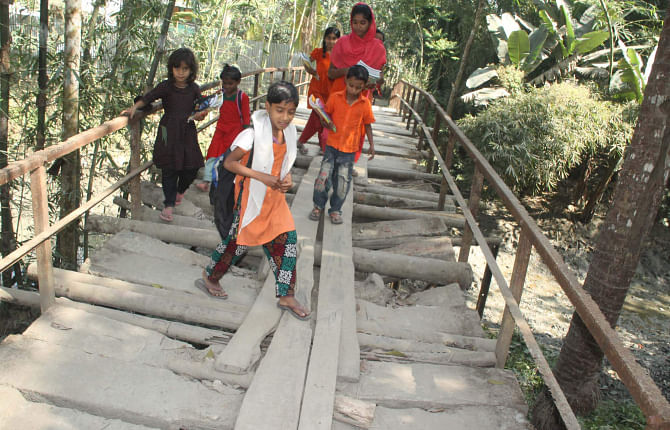 Kids take a risky walk on this awfully dilapidated iron bridge to cross Lakutia canal in Barisal Sadar upazila a couple of days ago as the authorities concerned did not take any step to repair the structure for long.  PHOTO: STAR