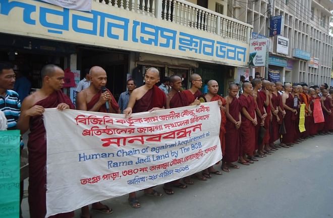 Buddhist monks form a human chain in front of Bandarban Press Club yesterday, protesting a BGB move to acquire 25 acres of land in Taracha area of Rowangchhari upazila of the district.  Photo: Star