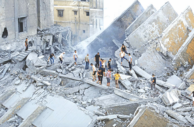 People inspect the remains of a high rise building destroyed by an Israeli air strike. Photo: AFP