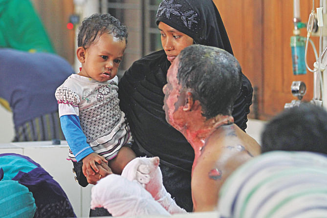 Unai looking at the burnt face of his father Khokan at the burn unit of Dhaka Medical College Hospital yesterday. Khokan got burnt when criminals hurled a petrol bomb at a bus in Jatrabari Friday night.  Photo: Amran Hossain