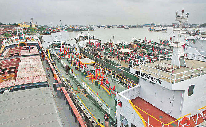 Cargo carriers which ply inland waterways lie anchored by the Karnaphuli river while workers sit idle, inset, following an indefinite countrywide strike they called yesterday after seven people aboard a fertiliser-laden lighter vessel went missing in Laxmipur the night before following what they said a robbery. Photo: Star