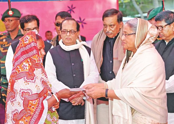 Prime Minister Sheikh Hasina hands over a cheque to a victim of the atrocities carried out on the Hindus at Malopara of Abhaynagar in Jessore right after the January 5 polls. The PM went to visit the area yesterday.  Photo: PID
