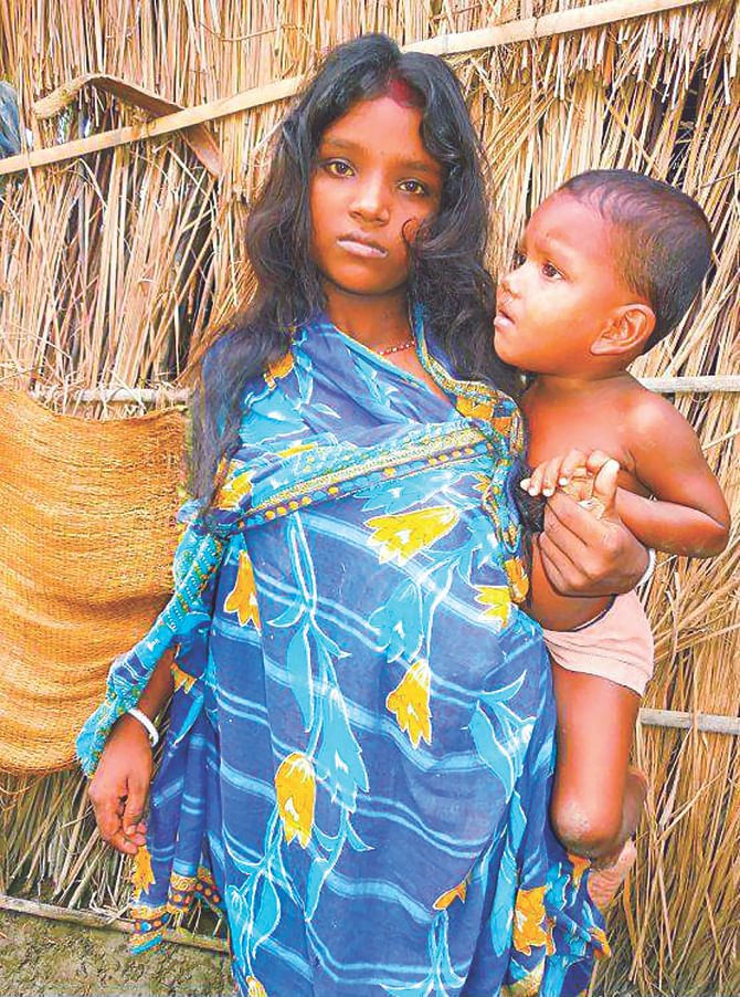 Little Shilpi Rani of Badia community in Jaldhaka of Nilphamari poses with her child in the lap in front of her hut. PHOTO: STAR