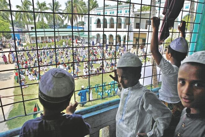 Children of Nuria Madrasa in Kamrangirchar watch as a few hundred Hefajat-e Islam men under the banner Bangladesh Khelafat Andolan gather at their madrasa premises for a demonstration. Police foiled the protesters' attempt to bring out a procession marking the first anniversary of what they say was police excess at Shapla Chattar in Motijheel.  Photo: Rashed Shumon