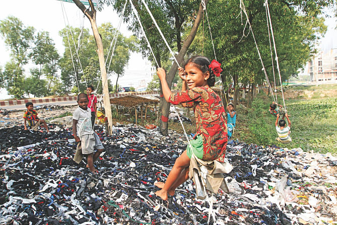 Children playing on swings they made from garment-waste dumped beside Dhaka-Aricha highway at Rajfulbaria in Savar yesterday. Thousands of children are still deprived of their basic rights in Bangladesh as the world observes the 25th anniversary of Convention on the Rights of the Child yesterday. Photo: Palash Khan