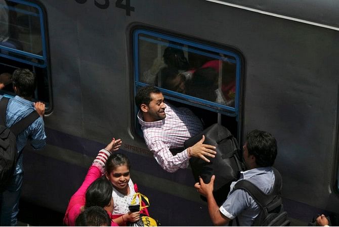 A passenger squeezes in through the window of a stationary train at a railway station in Jammu, India. Photo: Reuters/File