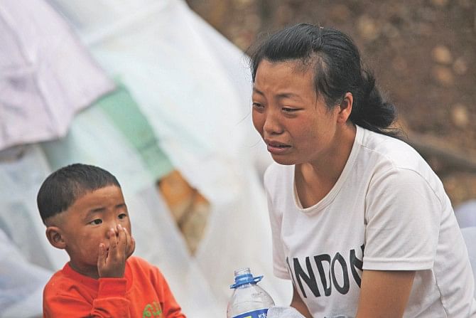 A woman (R) cries in Ludian county in Zhaotong, southwest China's Yunnan province yesterday. Rescuers laid out bodies in the streets after at least 398 people were killed by an earthquake in China, leaving the idyllic mountain landscape littered with scenes of devastation and sparking a huge rescue effort.  Photo: AFP