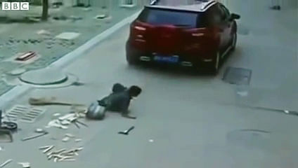 A still grab from the surveillance footage showing a Chinese boy pulling himself after being run over by an SUV.