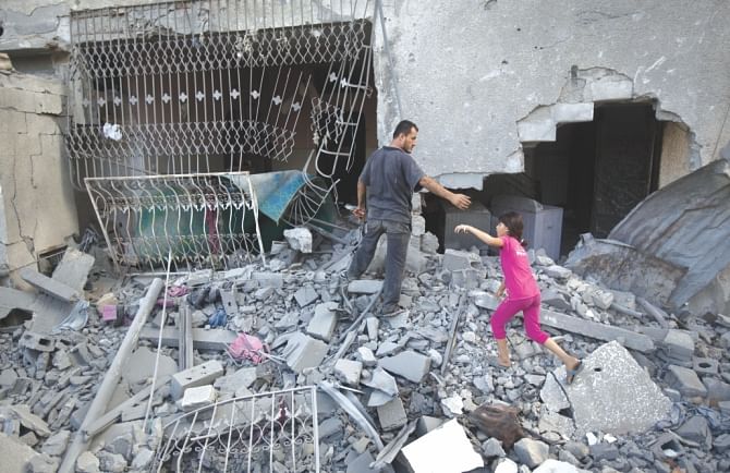 Palestinians walk through the rubble of a house. Photo: AFP
