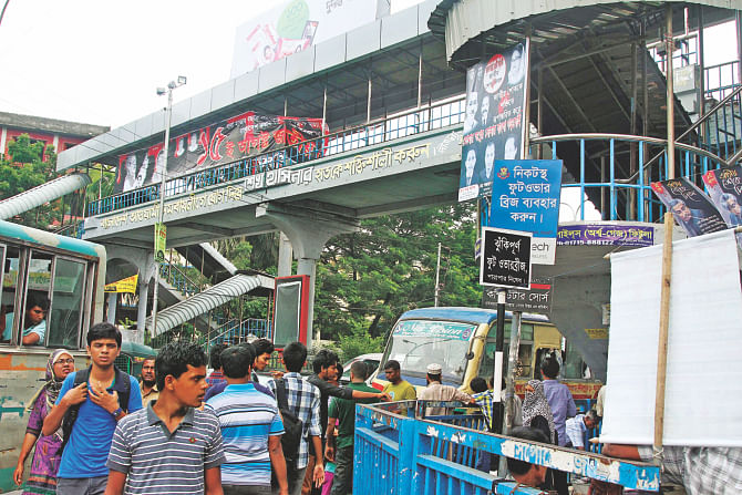 The footbridge is there at Farmgate but a sign, top, asks pedestrians to use other bridges close by. The bridge has been out of commission for over a month with no sign of authorities concerned trying to repair it.  Photo: Sk Enamul Haq
