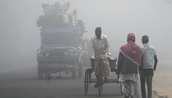 In poor visibility, slow-moving rickshaw-vans ply and people walk on the Chittagong-Cox's Bazar highway at Patia as vehicles at speed whizz by them early yesterday. The fog kept Chittagong and its surrounding areas covered almost until noon. Photo: Anurup Kanti Das
