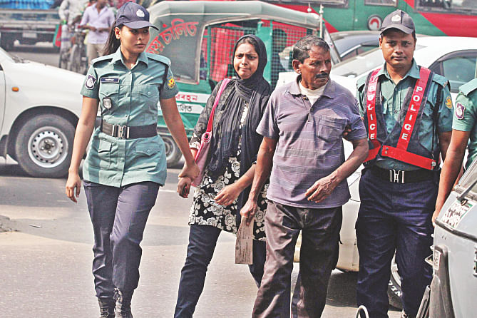 Cops grab jaywalkers by the hand and lead them to mobile courts set up nearby on Kazi Nazrul Islam Avenue yesterday.  Photo: Star