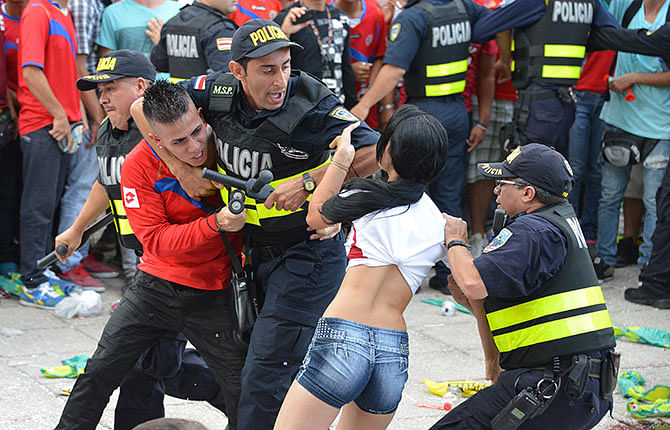 Policemen arrest Costa Rican fans after three men were stabbed while watching the Brazil 2014 FIFA World Cup football match against Netherlands receives medical attention, at Democracy Square in San Jose. Photo: Getty Images