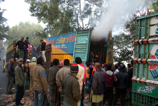 Smoke rises out of a truck laden with boxes of biscuit packets after it was petrol-bombed in Amtoli area on the Dhaka-Dinajpur highway early yesterday.   Photo: Star