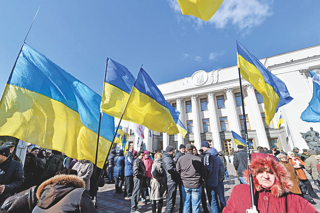 People hold Ukrainian flags as they gather in front of the parliament in Kiev yesterday. Ukrainian troops will remain in Crimea, the country's defence minister said that day even as media reported the separatist peninsula planned to disband Ukrainian units there. Photo: AFP