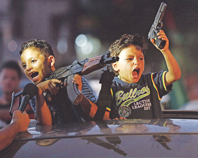 Children hold up guns from a car to celebrate the deal. Photo: AFP