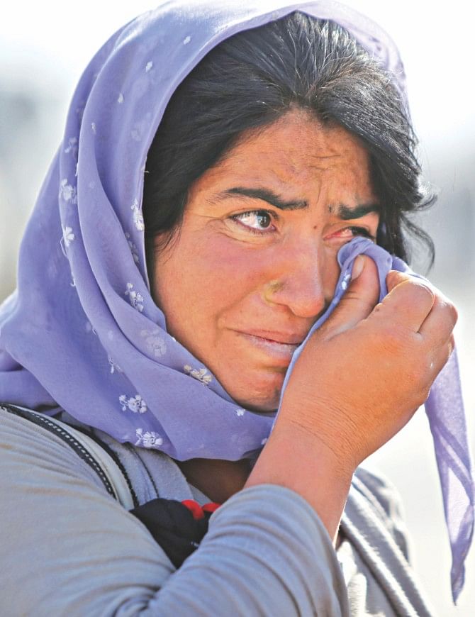 A displaced Iraqi Yazidi woman wipes her eyes. Photo:  AFP