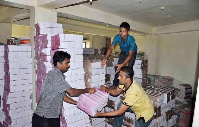 Printers cannot give delivery of textbooks due to hartals and blockades. Photo shows staff of a press at Kandir Par in Comilla city pile up books in storeroom. PHOTO: STAR