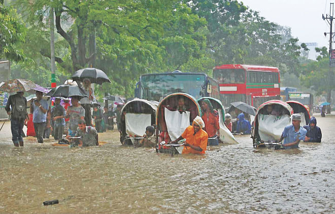 Pedestrians and vehicles move through waist-deep water accumulated in Sholoshahar area of Chittagong city yesterday morning. People in the port city are having a tough time as torrential rains since Thursday have inundated vast areas. Photo: Anurup Kanti Das 