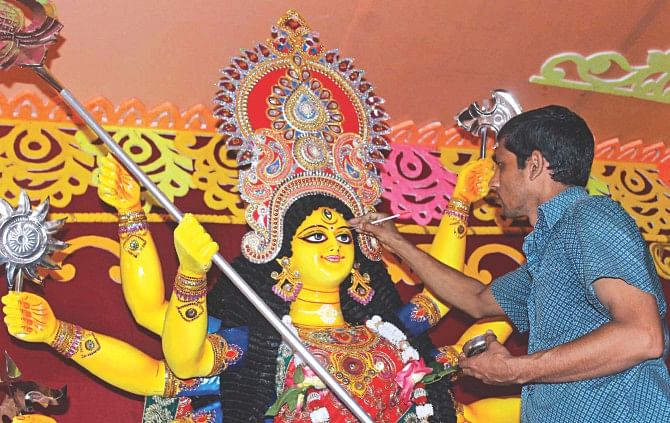 An artisan puts the finishing touches to an idol of Durga in Kalibari temple in Barisal city yesterday on the eve of Durga Puja, the biggest festival of Bangalee Hindus. Photo: Arifur Rahman