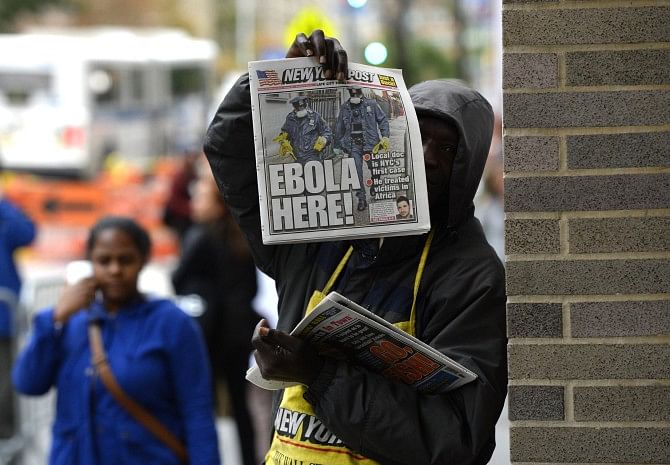 A newspaper vendor holds up a copy of the NY Post in front of the entrance to Bellevue Hospital in New York yesterday morning after officials confirmed New York's first case of Ebola. Photo: AFP