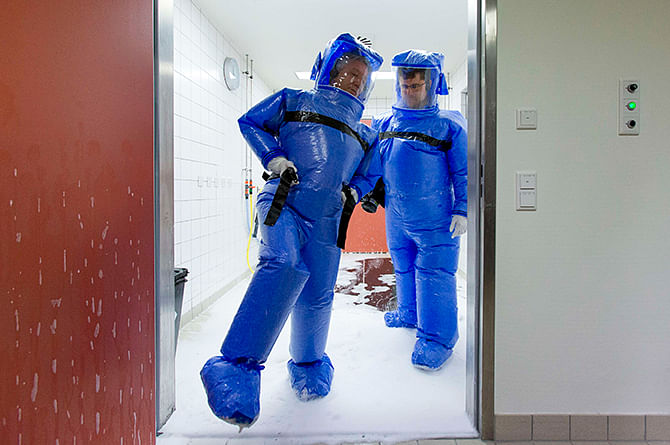 Doctor for tropical medicine Florian Steiner (R) and ward physician Thomas Klotzkowski step out of a disinfection chamber after cleaning their protective suits, at the quarantine station for patients with infectious diseases at the Charite hospital in Berlin August 11. Photo: Reuters