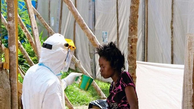 A health worker offers water to a woman with Ebola in Kenema, Sierra Leone, in July 2014. World Health Organization experts say it will take months to bring the outbreak under control. Photo: BBC