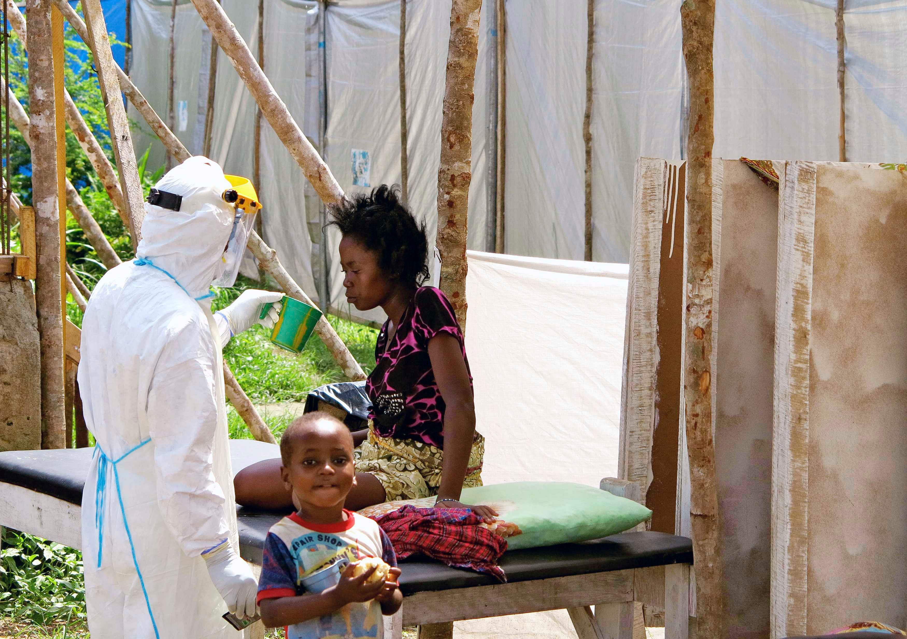 A health worker, wearing personal protection gear, offers water to a woman with Ebola virus disease (EVD), at a treatment centre for infected persons in Kenema Government Hospital, in Kenema, Eastern Province, Sierra Leone in this August, 2014 handout photo provided by UNICEF August 6, 2014. Workers in the treatment centre are stretched to capacity. UNICEF is supporting the hospital by providing treatment supplies like intravenous fluids and equipment such as protective gear and body bags. As of 4 August, a total of 1,711 cases, including 932 deaths, had been attributed to EVD in the four West African countries of Guinea, Liberia, Nigeria and Sierra Leone. Sierra Leone has borne 691 of these cases (576 confirmed, 49 probable and 66 suspected), including 286 deaths. Photo: Reuters