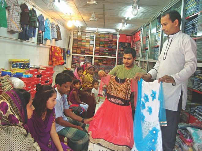 Two dresses named after popular Indian TV character Pakhi being shown to a girl at a market in Jhenidah.  Photo: Star