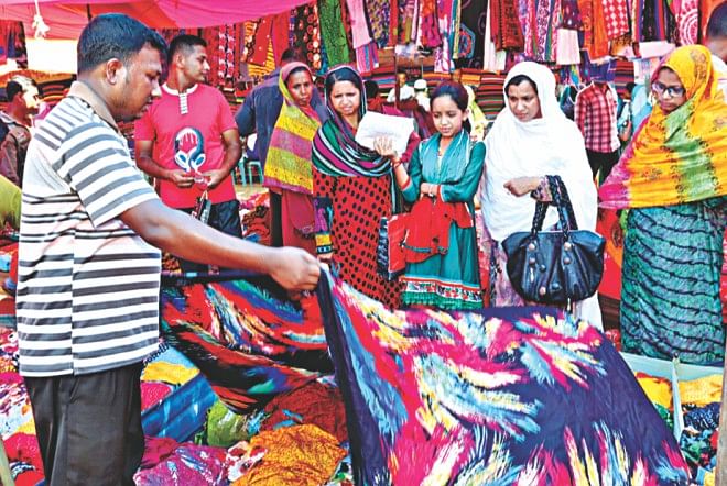 Women look at a sari in Bogra Railway Hawkers Market.  Photo: Star