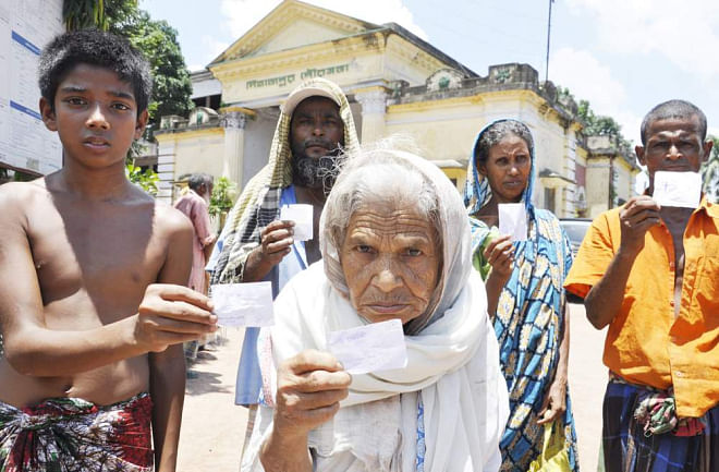 Five members of ultra poor families show their VGF cards issued by Dinapur municipality to provide them with only 3kg of rice instead of 10 kg under special Eid programme at the premises of the municipality office yesterday. Photo: Star