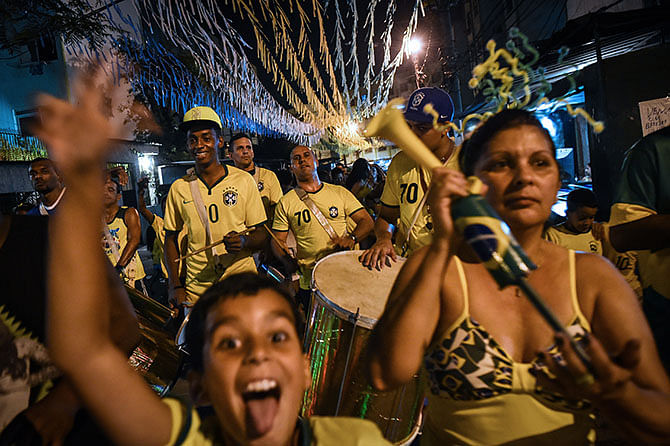 A local drum band marches along the street as children accompany in Jacarezinho shantytown (favela) in Rio de Janeiro, Brazil, celebrating Brazil's 2-1 victory over Colombia