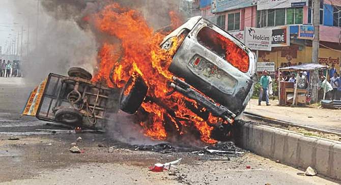 This Star photo taken on May 20 shows the car of Phulgazi upazila chairman Ekramul Haq burning after an arson attack in Feni. The easy bike used by the attackers is also in flames. 