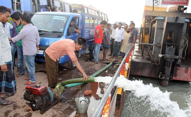 To keep a ferry operational, a worker pumps out water that had entered through the cracks of the vessel at Lebukhali terminal on the Paira River on  Barisal-Patuakhali road.   PHOTO: STAR
