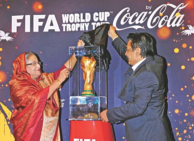 WORLD CUP IN DHAKA: Prime Minister Sheikh Hasina unveils the FIFA World Cup trophy at the Gono Bhaban yesterday. The coveted trophy is making its maiden visit to Bangladesh as part of its world tour. The most prestigious global sporting piece of glory will remain at the Radisson Hotel as all the scheduled trophy display programmes billed for the Bangabandhu National Stadium for today and tomorrow will now be held at the posh hotel. PHOTO: PID